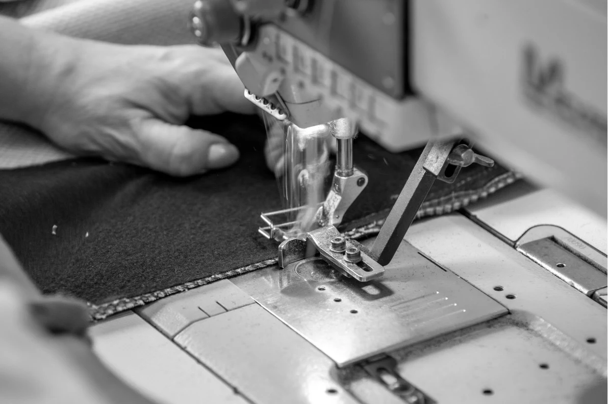A sewing machine presser foot guiding a seam in upholstery fabric