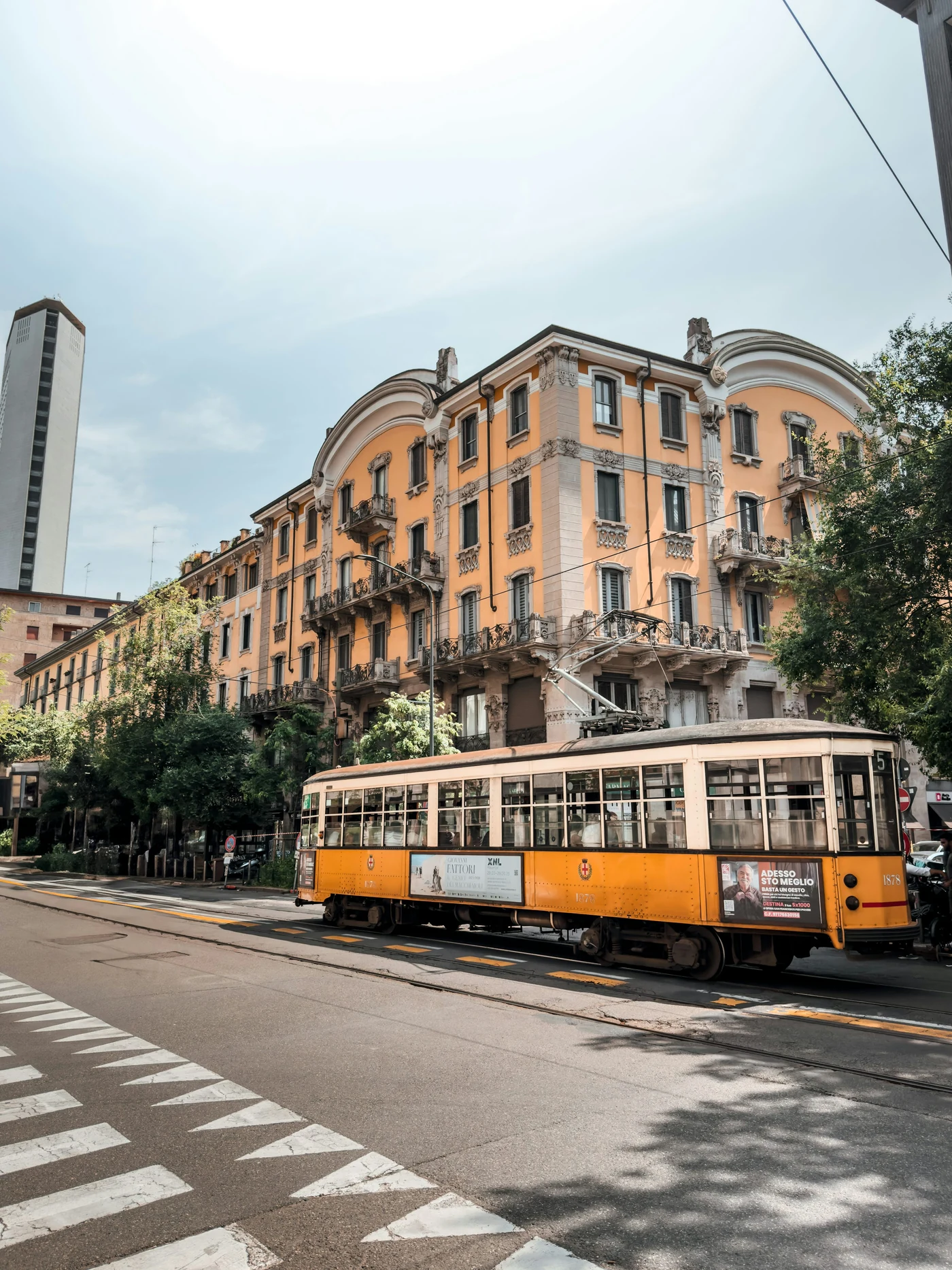 A yellow tram on a street in Milan.
